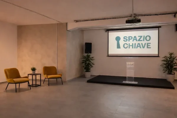 Sala presentazioni con palco e schermo – set di Radio Aut a Spazio Chiave
